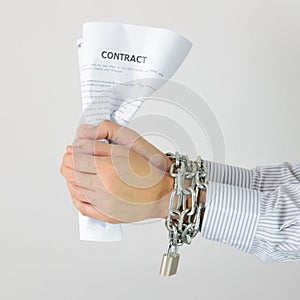Businessman hands with chains and contract