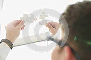 Businessman hands connecting puzzle pieces representing the merging of two companies or joint venture, partnership