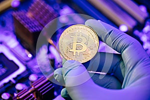 Businessman hands in gloves hold gold Bitcoin on motherboard background. Cryptocurrency in the fingers. Person shows