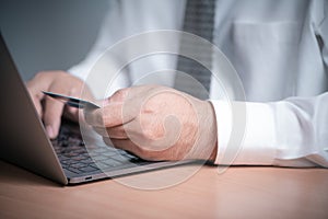 Businessman hands holding credit card and using laptop