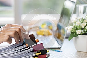 Businessman hands holding pen for working in Stacks of paper files searching information business report papers and piles of