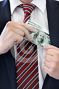 Businessman, hands and money bribe in pocket for fraud, scam or secret on a white studio background. Closeup of employee
