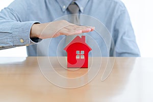 Businessman hands protecting red house model residential concept of home protection, insurance, real estate investment. with a