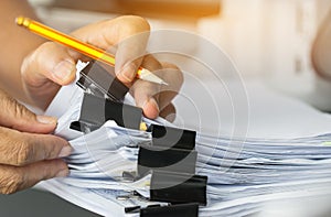 Businessman hands searching and checking write unfinished documents stacks of paper files on office desk for report papers with