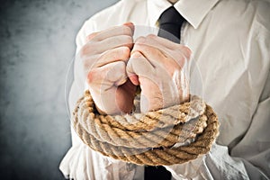 Businessman with hands tied in ropes