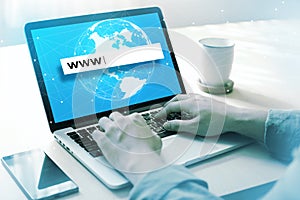 Businessman hands tying www in text box on laptop computer with global connection background on screen.