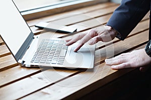 Businessman hands with watch working on laptop, finger touching the touchpad. Close up