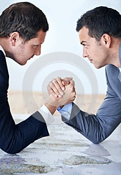 Businessman, handshake and arm wrestle for competition, challenge or strength on table at the office. Serious man photo