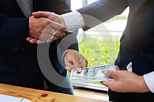 Businessman handshake and dollar banknotes in hands. Dishonest cheating in business illegal money,Bribery and corruption concept.