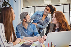 Businessman with happy female coworkers at desk