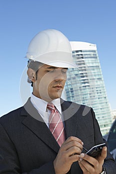 Businessman In Hardhat Using PDA