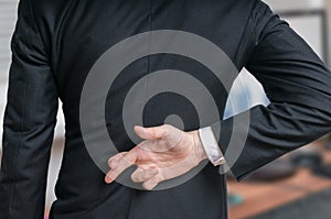 Businessman has crossed fingers behind his back. Good luck or dishonesty concept photo