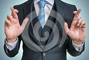 Businessman has crossed fingers behind his back. Good luck or dishonesty concept photo