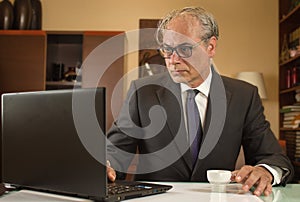 businessman having coffee and working from home telecommuting due pandemic with laptop