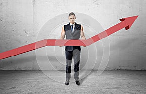 Businessman having muscular arms and holding big red line graph with an upturned arrow