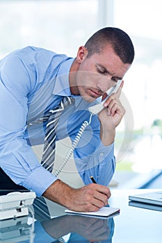 Businessman having a phone call and writing notes