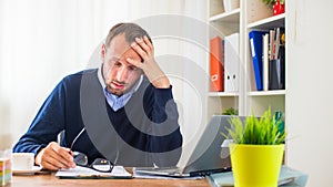 Businessman with headache sitting in his office.