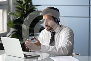 Businessman in headphones makes videocall chatting with partner consulting client