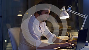 Businessman in headset with laptop at night office