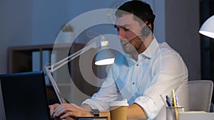 Businessman in headset with laptop at night office