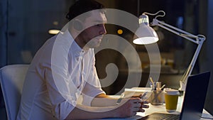 Businessman in headset with laptop at night office