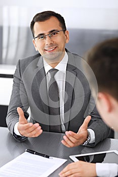 Businessman headshot at meeting in modern office. Entrepreneur sitting at the table with colleagues. Teamwork and