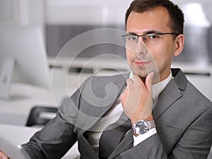 Businessman headshot at meeting in modern office. Entrepreneur sitting at the table with colleagues. Teamwork and