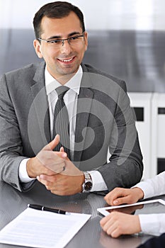 Businessman headshot at meeting in modern office. Entrepreneur sitting at the table with colleagues. Teamwork and