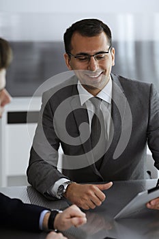 Businessman headshot at meeting in modern office. Entrepreneur sitting at the table with colleagues. Teamwork and