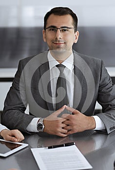 Businessman headshot at meeting in modern office. Entrepreneur sitting at the table with colleagues. Teamwork and