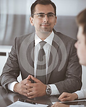 Businessman headshot at meeting in modern office. Entrepreneur sitting at the table with colleagues. Teamwork and