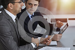 Businessman headshot at meeting in modern office. Entrepreneur sitting at the table with colleagues. Teamwork and