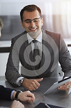 Businessman headshot at meeting in modern office. Entrepreneur sitting at the table with colleagues. Teamwork and