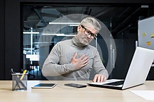 businessman heart attack at workplace, mature gray haired man working on laptop has severe chest pain heartache, senior