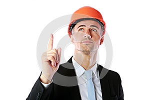 Businessman in helmet pointing up at copyspace