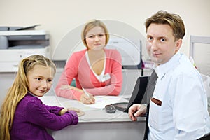 Businessman and her daughter sit in office of realtor.