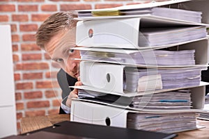 Businessman Hiding Behind The Folders Stack