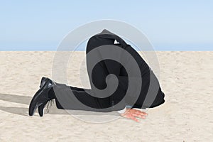 Businessman hiding his head in sand