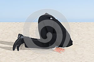 Businessman hiding his head in sand photo