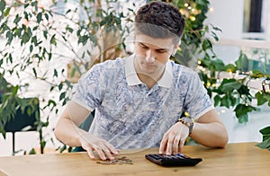 Businessman at his desk with calculator counts coins in office