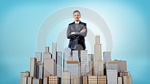 A businessman with his hands crossed standing behind a small model of a business district.