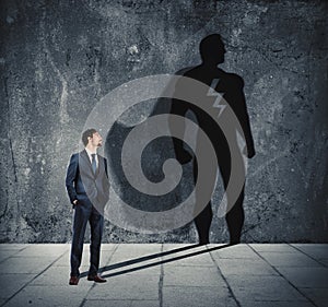 Businessman with his shadow of super hero on the wall. Concept of powerful man photo