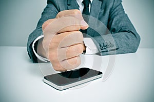 Businessman hitting a smartphone with his fist