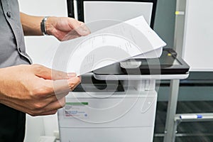 Businessman hold paper for scanning on the office printer