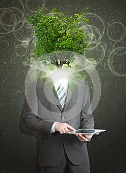 Businessman hold tablet pc. Green tree instead his