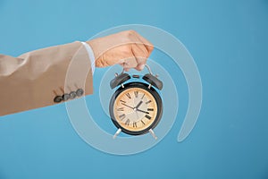 Businessman holding alarm clock on color background. Time management concept