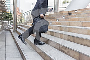 Businessman holding bag while walking upward on the stair outdoor in city