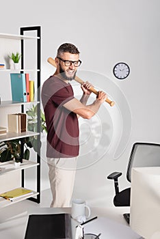 Businessman holding baseball bat near computer