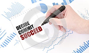 Businessman holding a black marker, notepad with text DECIDE COMMIT SUCCEED, business concept