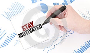 Businessman holding a black marker, notepad with text STAY MOTIVATED, business concept